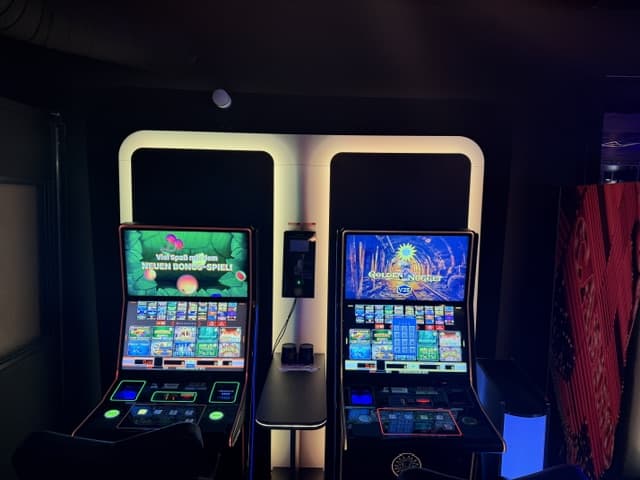 Zwei nebeneinander stehende Geldspielautomaten mit weißer LED-Umrandung und Bonusspiel-Anzeige