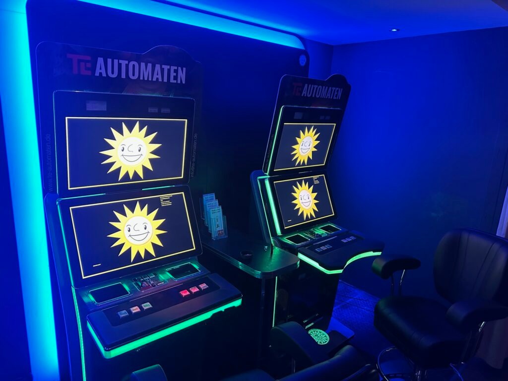 Multiple TE AUTOMATEN mit grüner LED-Beleuchtung in stimmungsvollem blauem Gaming-Raum