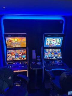 Zwei Gaming-Automaten mit bunten Displays unter dramatischer blauer LED-Beleuchtung